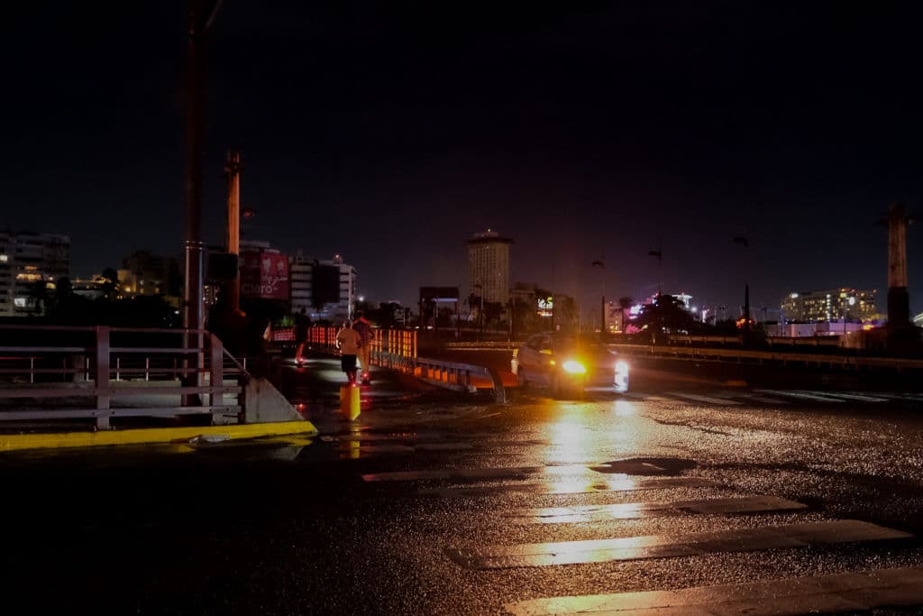 Los peatones usan linternas mientras caminan por una calle oscura en la comunidad de Condado de Santurce en San Juan, Puerto Rico, el 19 de septiembre de 2022. (AFP vía Getty Images)