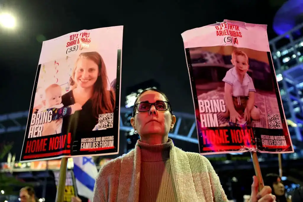 Una manifestante sostiene carteles con fotos de miembros de la familia Bibas, durante una protesta que pide la liberación de los rehenes cautivos en Gaza desde el ataque del 7 de octubre de 2023 por militantes palestinos de Hamás, frente al Ministerio de Defensa israelí en Tel Aviv el 19 de febrero de 2025. (Jack Guez/AFP vía Getty Images)