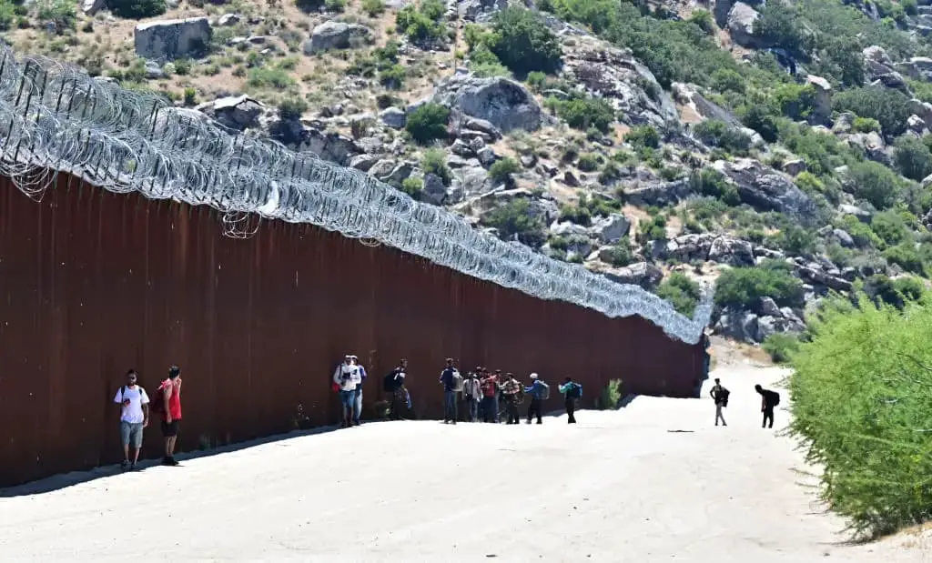Los migrantes caminan hacia los EE. UU. junto al muro fronterizo entre Estados Unidos y México en Jacumba Hot Springs, California, el 5 de junio de 2024. (Frederic J. Brown/AFP vía Getty Images)