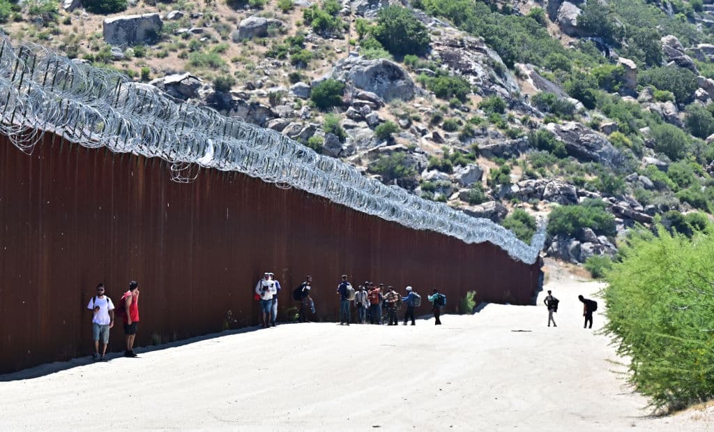 Los migrantes caminan hacia los EE. UU. junto al muro fronterizo entre Estados Unidos y México en Jacumba Hot Springs, California, el 5 de junio de 2024. (Frederic J. Brown/AFP vía Getty Images)