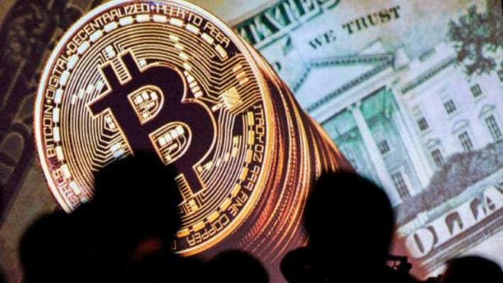 Representaciones gráficas de bitcoines y monedas estadounidenses se muestran en una pantalla mientras los delegados escuchan a los oradores durante el Congreso Mundial de INTERPOL, en Singapur, el 4 de julio de 2017. (Dominic Gwinn/AFP a través de Getty Images)