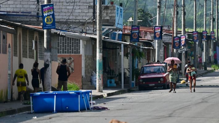 Personas caminando por la calle en el barrio donde al menos 22 personas fueron asesinadas en la víspera en Guayaquil, Ecuador, el 7 de marzo de 2025. (Marcos Pin/AFP vía Getty Images)