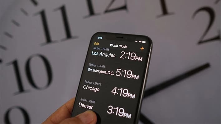 Un reloj detrás de un teléfono inteligente que muestra la hora después del horario de verano que se implementó en Los Ángeles el 15 de marzo de 2022. (Chris Delmas/AFP a través de Getty Images)
