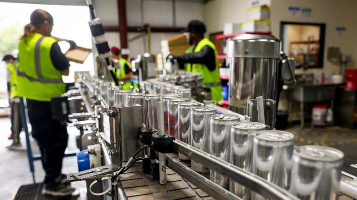 Latas de cerveza recién enlatada se mueven a lo largo de una línea de montaje en la sede de The Can Van, en Sacramento, California, el 19 de febrero de 2025. Los cerveceros artesanales se preparan para un arancel del 25 por ciento sobre las importaciones de aluminio, que entrará en vigor el 12 de marzo bajo el mandato del presidente Donald Trump, lo que podría elevar los precios de la cerveza y los refrescos enlatados. (Justin Sullivan/Getty Images)