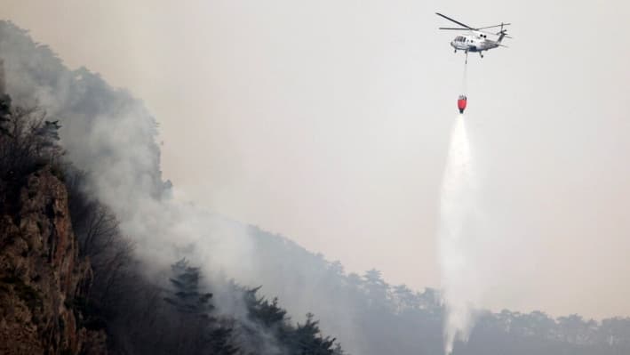 Un helicóptero intenta extinguir un incendio forestal arrojando agua en un parque nacional en Cheongsong, Corea del Sur, el 27 de marzo de 2025. (Lee Moo-yeol/Newsis vía AP)