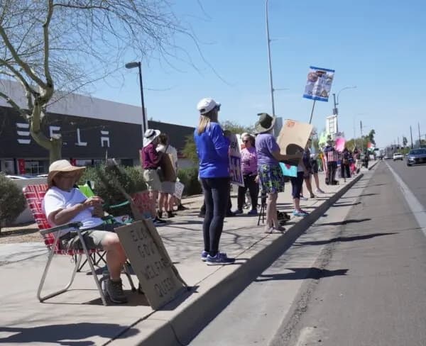 Manifestantes contra Elon Musk se reúnen en un concesionario de Tesla en Tempe, Arizona, el 22 de marzo de 2025. (Allan Stein/The Epoch Times)