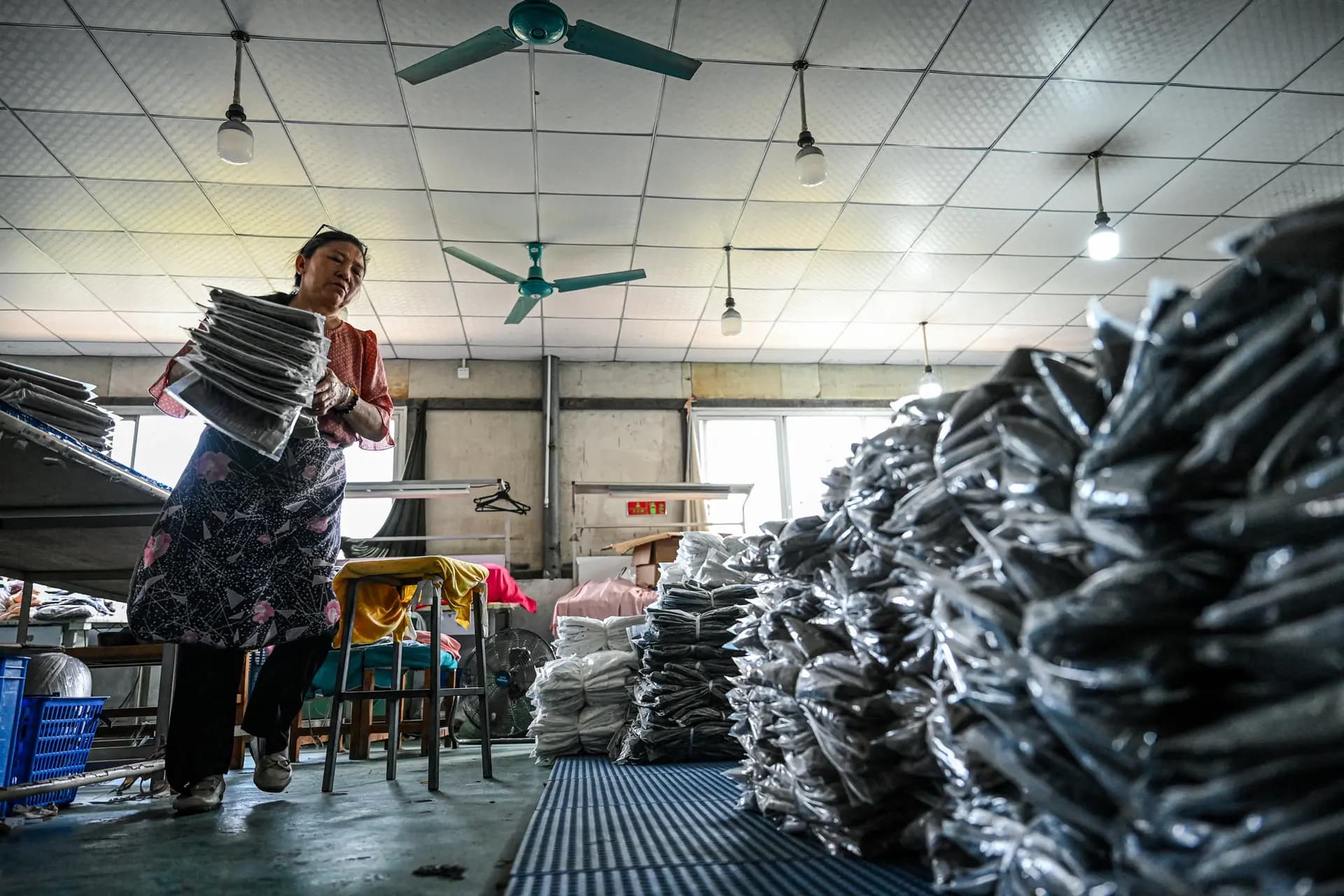 Un empleado clasifica prendas para las plataformas de comercio electrónico chinas Temu en una fábrica de ropa en Guangzhou, provincia de Guangdong, China, el 16 de abril de 2025. Algunos trabajadores chinos han publicado en las redes sociales quejas sobre su despido temporal. (Jade Gao/AFP a través de Getty Images).
