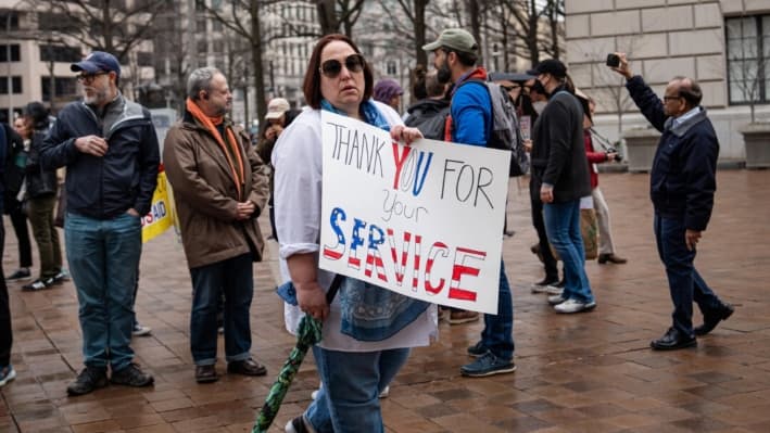 La gente se encuentra afuera en apoyo a los empleados de USAID que salen del edificio en Washington, el 27 de febrero de 2025. (Madalina Vasiliu/The Epoch Times)