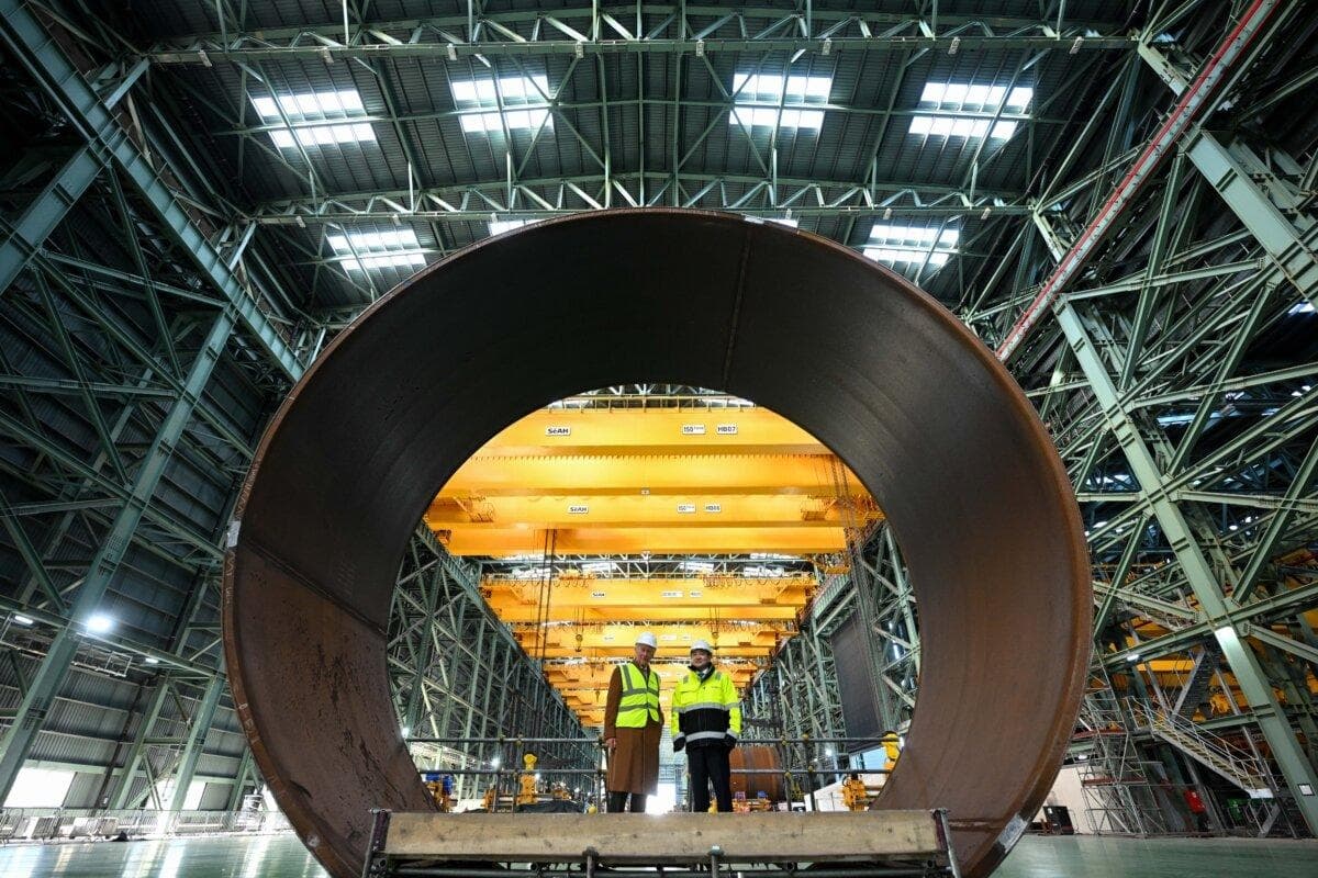 El rey Carlos III (izquierda) y el presidente de SeAHn Steel, Joosung Lee, de pie en la sección de una cimentación monopilote durante una visita a la fábrica de SeAH, en Middlesbrough, Inglaterra, el 13 de febrero de 2025. (Oli Scarff - WPA Pool/Getty Images)
