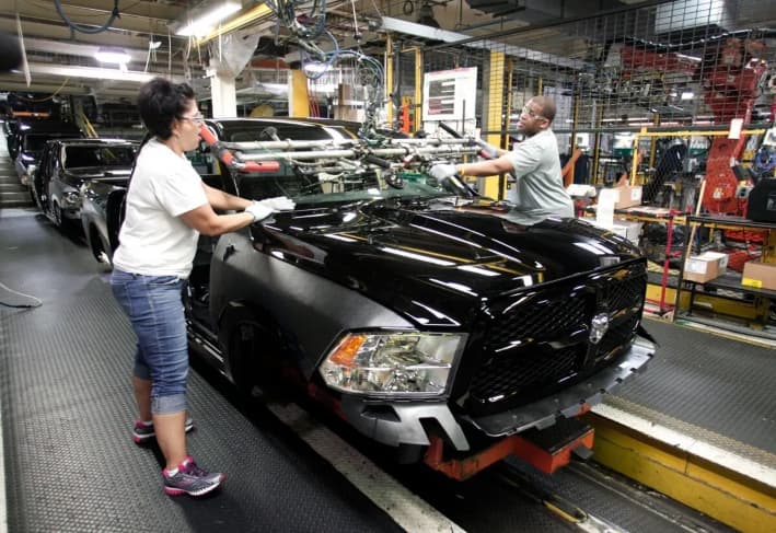 Trabajadores instalan un parabrisas en una camioneta Ram 1500 en la línea de montaje de la planta de montaje de camiones de Warren, en Michigan, el 25 de septiembre de 2014. La planta era operada por Chrysler, que ahora forma parte de Stellantis. (Bill Pugliano/Getty Images)