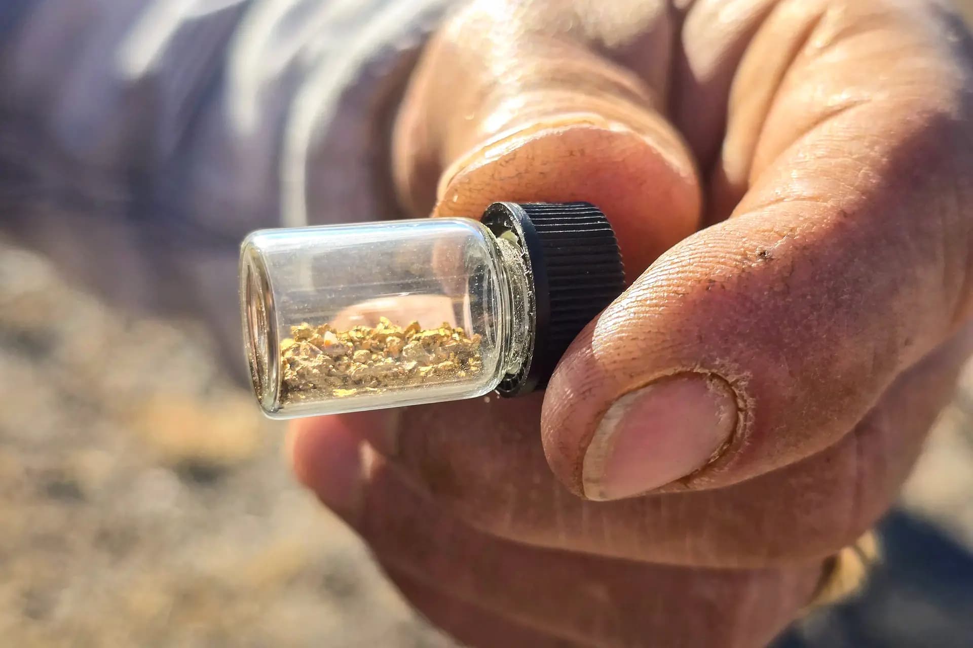 <em>Joe Marihugh, de Tucson, Arizona, muestra un frasco que contiene aproximadamente 1 gramo de escamas de oro que extrajo de cubos de arena a través de una lavadora, el 22 de marzo de 2025. Allan Stein/The Epoch Times</em>