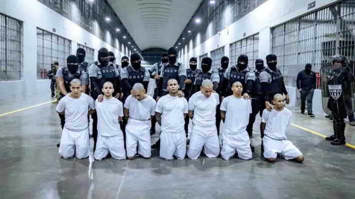 Guardias penitenciarios salvadoreños escoltan a presuntos miembros de la pandilla venezolana Tren de Aragua y la pandilla MS-13, recientemente deportados por el gobierno de Estados Unidos para ser encarcelados en el Centro de Internamiento de Terroristas (CECOT), como parte de un acuerdo con el gobierno salvadoreño, en Tecoluca, El Salvador, el 30 de marzo de 2025. (Secretaría de Prensa de la Presidencia/Reuters)
