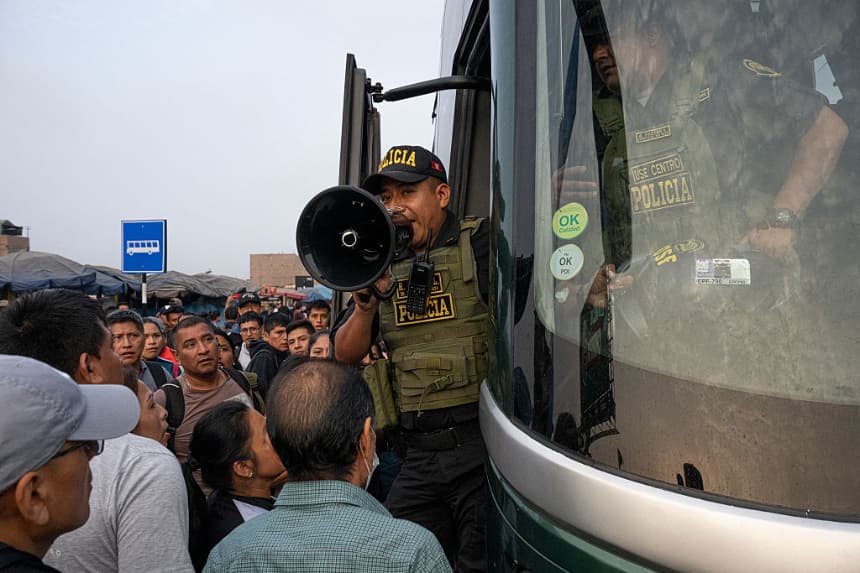 Un policía da instrucciones a las personas que esperan para abordar un autobús policial durante un paro convocado por las empresas de transporte público contra la extorsión y exigiendo mayor seguridad, en Lima (Perú), el 10 de abril de 2025. (Ernesto Benavides/AFP vía Getty Images)