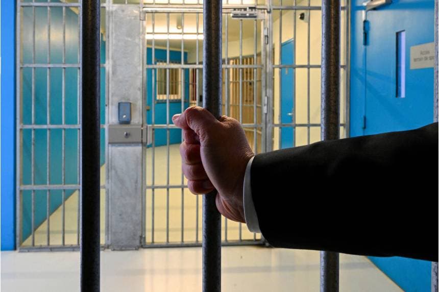 Un funcionario de la administración penitenciaria se aferra a una puerta de seguridad dentro del centro penitenciario de Vendin-le-Vieil, en Francia, el 10 de abril de 2025. (Foto de FRANCOIS NASCIMBENI/AFP a través de Getty Images).