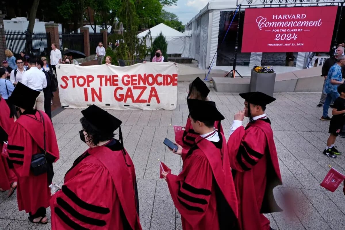 Estudiantes de la Universidad de Harvard pasan junto a manifestantes mientras entran en el Harvard Yard para la ceremonia de graduación en la Universidad de Harvard, en Cambridge, Massachusetts, el 23 de mayo de 2024. (Charles Krupa/AP Photo)
