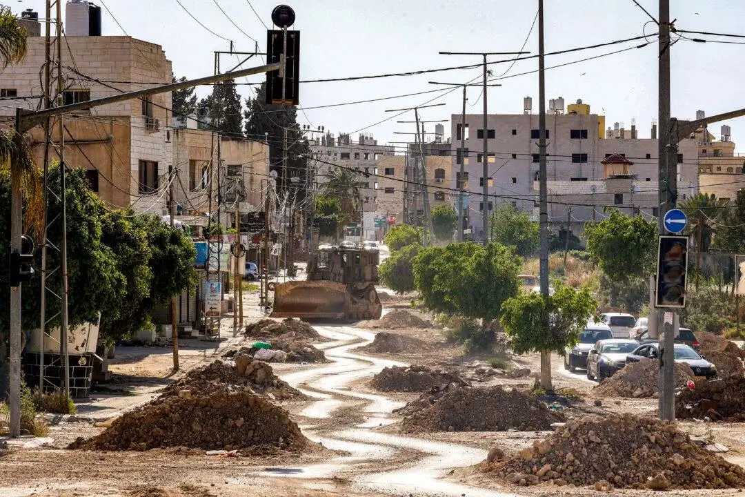 Una excavadora militar israelí junto a una carretera parcialmente demolida durante una operación del ejército en los campos de refugiados palestinos de Tulkarem, en el noroeste de la Cisjordania ocupada, el 16 de abril de 2025. (Zain Jaafar/AFP).