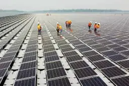 Trabajadores caminan entre paneles de células solares sobre la superficie del agua de la presa Sirindhorn en Ubon Ratchathani, Tailandia, el 8 de abril de 2021. (Prapan Chankaew/Reuters).