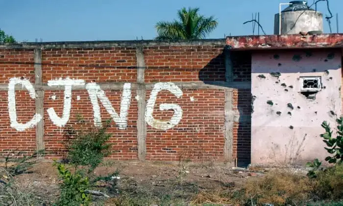 Vista de una pared acribillada a bala con las iniciales del grupo criminal Cartel Jalisco Nueva Generación (CJNG) a la entrada de la comunidad de Aguililla, en el estado de Michoacán (México), el 23 de abril de 2021. (Enrique Castro/AFP a través de Getty Images.)
