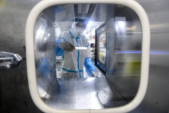 Un técnico de laboratorio trabaja con muestras para analizarlas en busca de COVID-19 en el laboratorio Fire Eye, un centro de pruebas de COVID-19, en Wuhan, China, el 5 de agosto de 2021. (STR/AFP vía Getty Images)