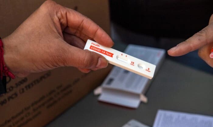 Voluntarios explican cómo utilizar una prueba rápida de COVID-19 para uso doméstico en Chelsea, Massachusetts, el 17 de diciembre de 2021. (Joseph Prezioso/AFP a través de Getty Images).