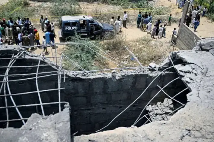 Residentes se reúnen mientras la policía inspecciona el lugar donde supuestamente un dron fue derribado en Karachi, el 8 de mayo de 2025. (Rizwan Tabassum/AFP vía Getty Images)
