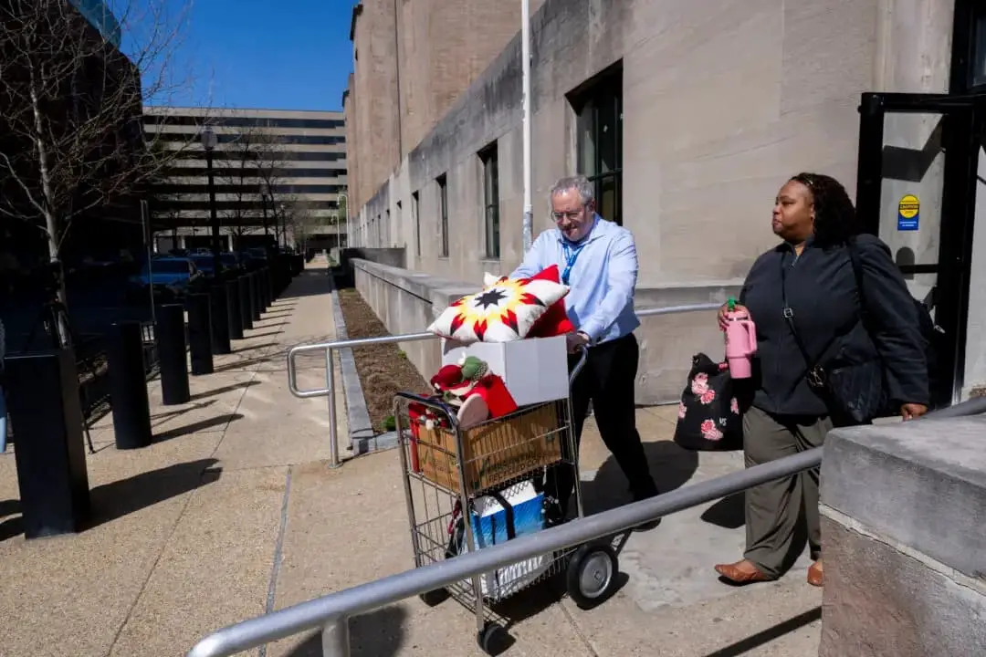 Una trabajadora federal (derecha), que perdió su trabajo, recibe ayuda para llevar algunas de sus pertenencias desde su oficina en el edificio Mary E. Switzer Memorial, que alberga el Departamento de Salud y Servicios Humanos de Estados Unidos, en Washington, el 1 de abril de 2025. (Roberto Schmidt/AFP a través de Getty Images)