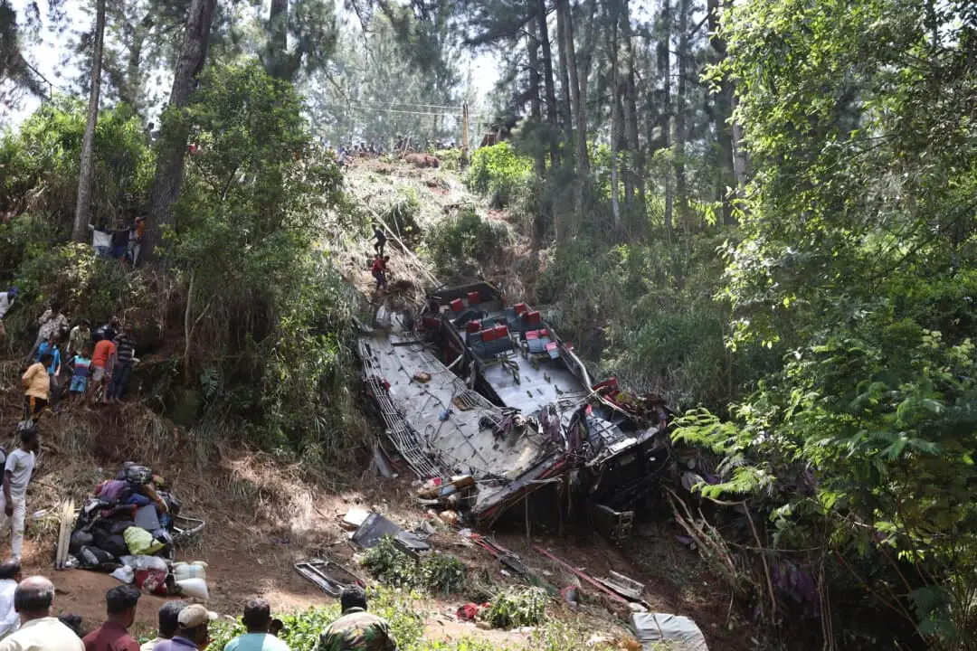 Los transeúntes observan cómo los equipos de rescate buscan entre los escombros en el lugar del accidente de autobús cerca de la ciudad de Kotmale, Sri Lanka, el 11 de mayo de 2025. (Foto AP.)