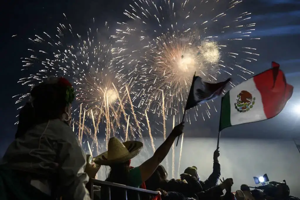 Fuegos artificiales y la gente ondeando banderas mexicanas en el Zócalo durante la ceremonia de "El Grito", que marcó el inicio de las celebraciones del Día de la Independencia en la Ciudad de México el 15 de septiembre de 2019. (PEDRO PARDO/AFP vía Getty Images)