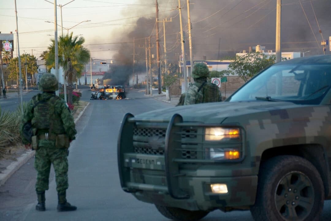 Soldados mexicanos montan guardia cerca de vehículos en llamas en una calle durante una operación para detener a Ovidio Guzmán, acusado de liderar una facción del famoso cártel de Sinaloa, en Culiacán, estado de Sinaloa (México), el 5 de enero de 2023. (Juan Carlos Cruz/AFP a través de Getty Images)

