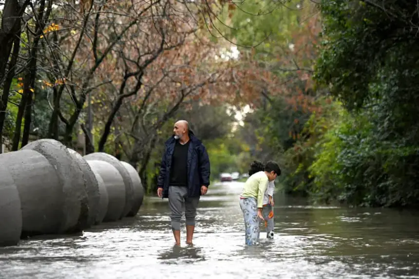 Personas caminan por una vía inundada el 17 de mayo de 2025, en el barrio La Bota (Argentina). EFE/ STR