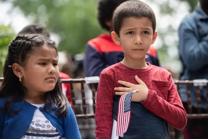 Dos niños escuchan el himno nacional de Estados Unidos durante una ceremonia especial de ciudadanía en la Casa de Lincoln, en Washington, D.C., el 31 de mayo de 2018. (NICHOLAS KAMM/AFP via Getty Images)