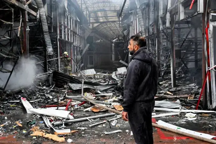 Un hombre observa cómo un bombero ucraniano apaga un incendio en el mercado de Barabashovo tras un ataque con drones en Járkov, Ucrania, el 6 de mayo de 2025. (Sergey Bobok/AFP vía Getty Images)