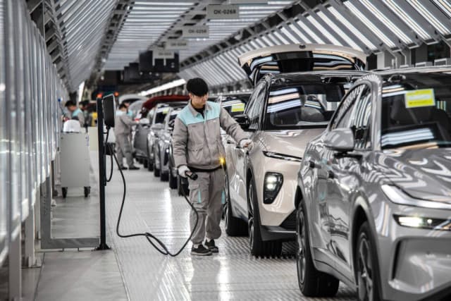 Un trabajador inspecciona el sistema de carga de un vehículo en Hefei, China, el 17 de enero de 2025. (Kevin Frayer/Getty Images)