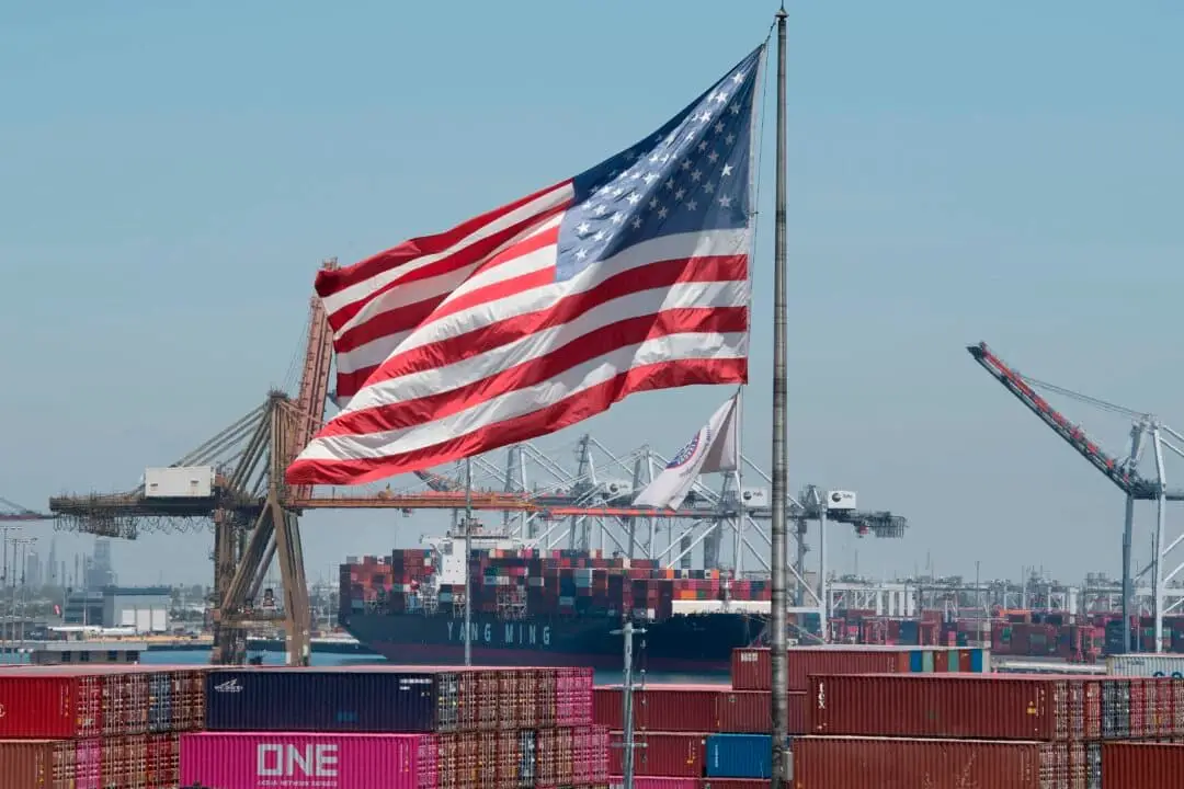La bandera estadounidense ondea sobre un buque portacontenedores que descarga su cargamento procedente de Asia en el puerto de Long Beach, California, el 1 de agosto de 2019. (Mark Ralston/AFP a través de Getty Images).