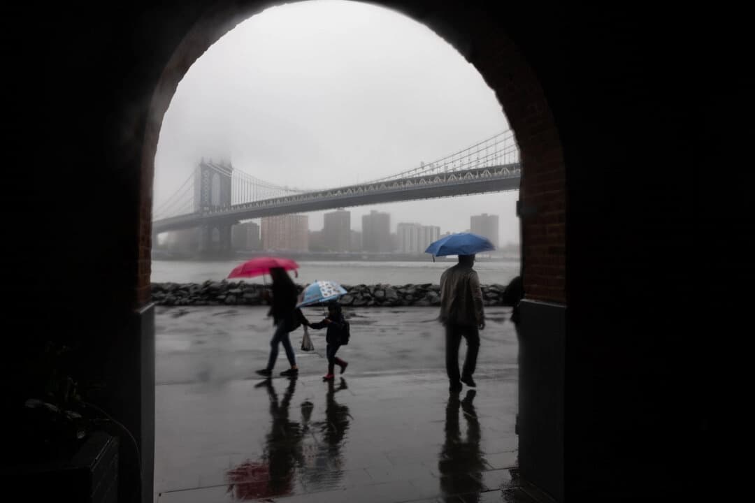 La gente camina bajo la lluvia frente al horizonte de Manhattan cubierto por la niebla en la ciudad de Nueva York el 6 de mayo de 2025. (Spencer Platt/Getty Images).