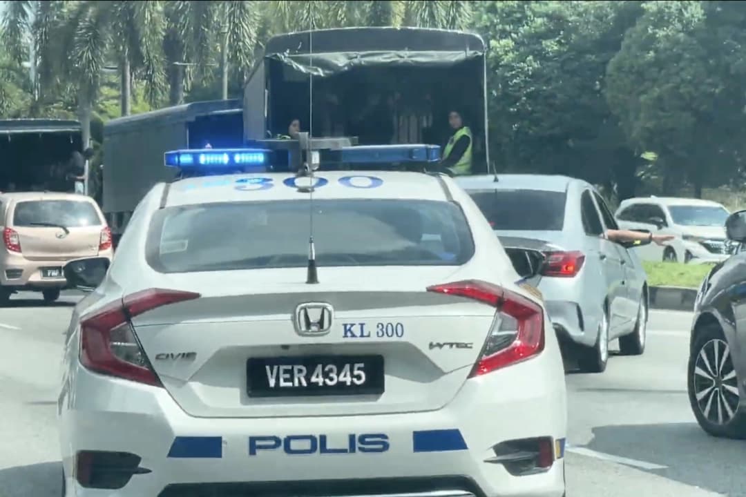 Vehículos policiales malayos escoltan furgonetas que transportan a practicantes de Falun Gong en Kuala Lumpur, Malasia, el 13 de abril de 2025. (The Epoch Times)
