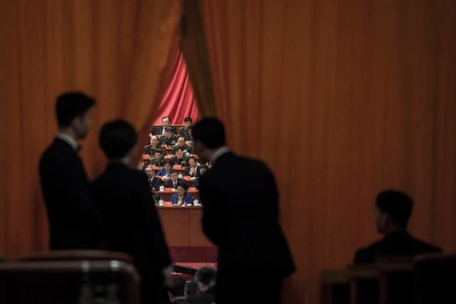 Guardias de seguridad chinos observan a los delegados militares durante el discurso del líder chino Xi Jinping en el XIX Congreso del Partido Comunista en Pekín, el 18 de octubre de 2017. (Fred Dufour/AFP a través de Getty Images).