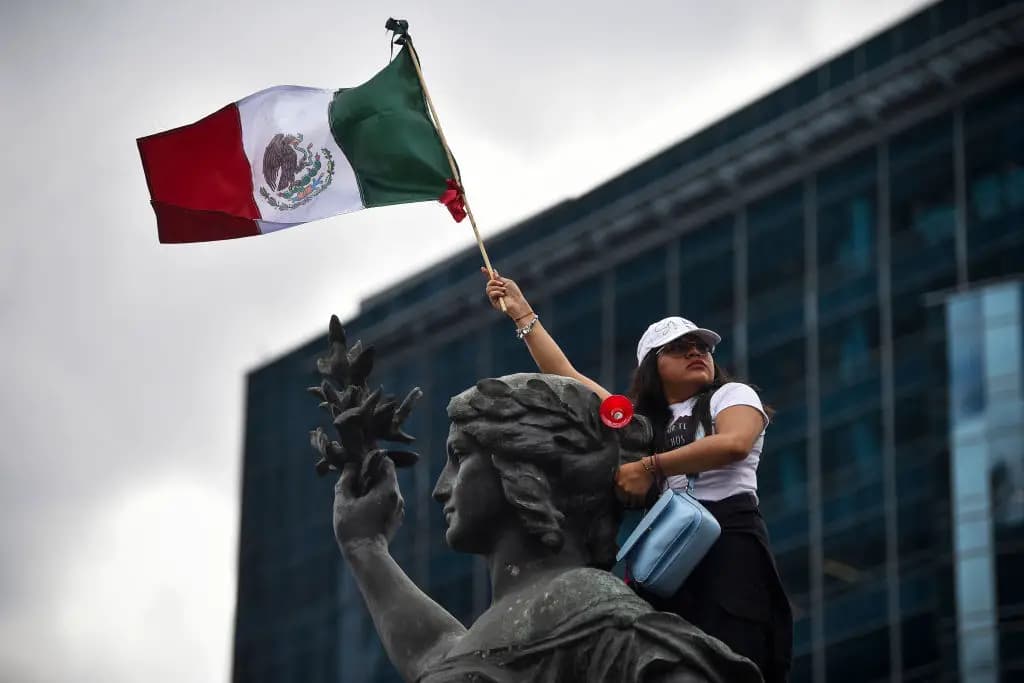 Una mujer sostiene una bandera mexicana mientras participa en una protesta tras la aprobación por el Senado de la reforma judicial propuesta por el gobierno en la glorieta del Ángel de la Independencia en la Ciudad de México el 11 de septiembre de 2024.  (RODRIGO OROPEZA/AFP vía Getty Images)