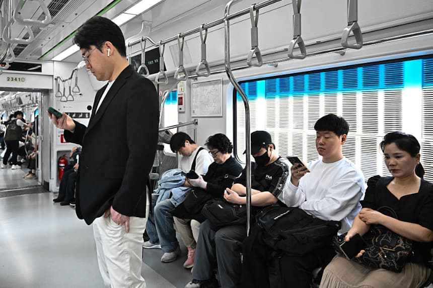 Los pasajeros usan sus teléfonos mientras viajan en un tren del metro en Seúl (Corea del Sur) el 28 de mayo de 2025. (Pedro Pardo/AFP vía Getty Images)