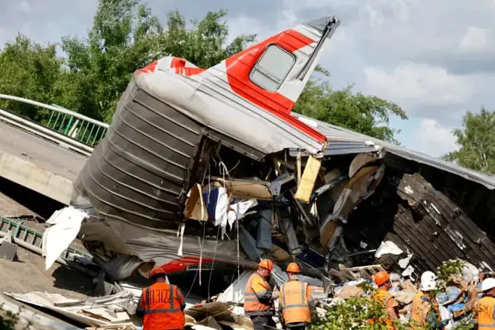 Especialistas de los servicios de emergencia se reúnen cerca de un vagón destruido, después de que un puente vehicular se derrumbara sobre vías férreas, descarrilando un tren que se aproximaba en la región de Bryansk, Rusia, el 1 de junio de 2025. (Stringer/Reuters)