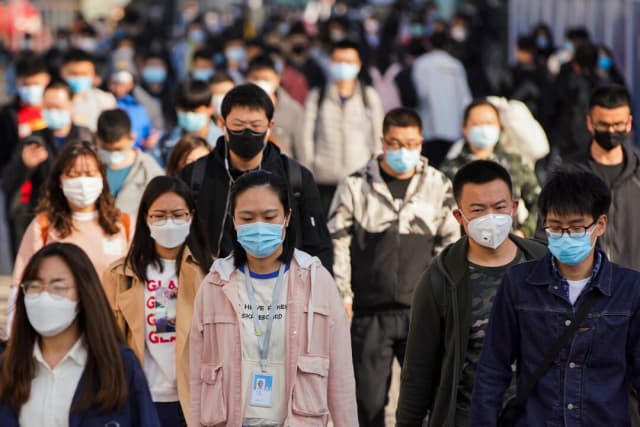 Los viajeros llevan mascarillas protectoras al salir de un tren en una estación de metro durante la hora pico del lunes en Beijing, China, el 13 de abril de 2020. (Lintao Zhang/Getty Images)