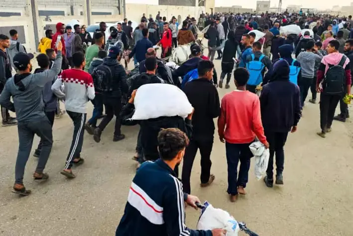 Palestinos desplazados, algunos con sacos de comida, abandonan un centro de distribución en Rafah, en el sur de la Franja de Gaza, el 1 de junio de 2025. (AFP vía Getty Images)