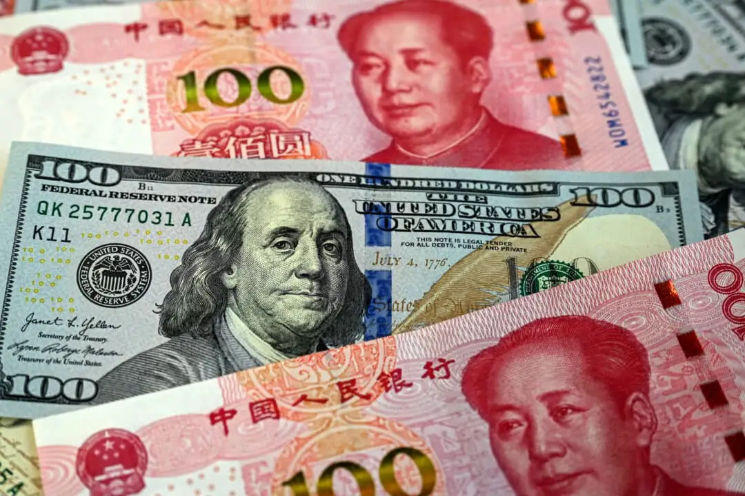 Esta ilustración fotográfica muestra billetes chinos de 100 yuanes (rojos) y billetes de 100 dólares estadounidenses, en Beijing, el 8 de abril de 2025. (Jade Gao /AFP a través de Getty Images)