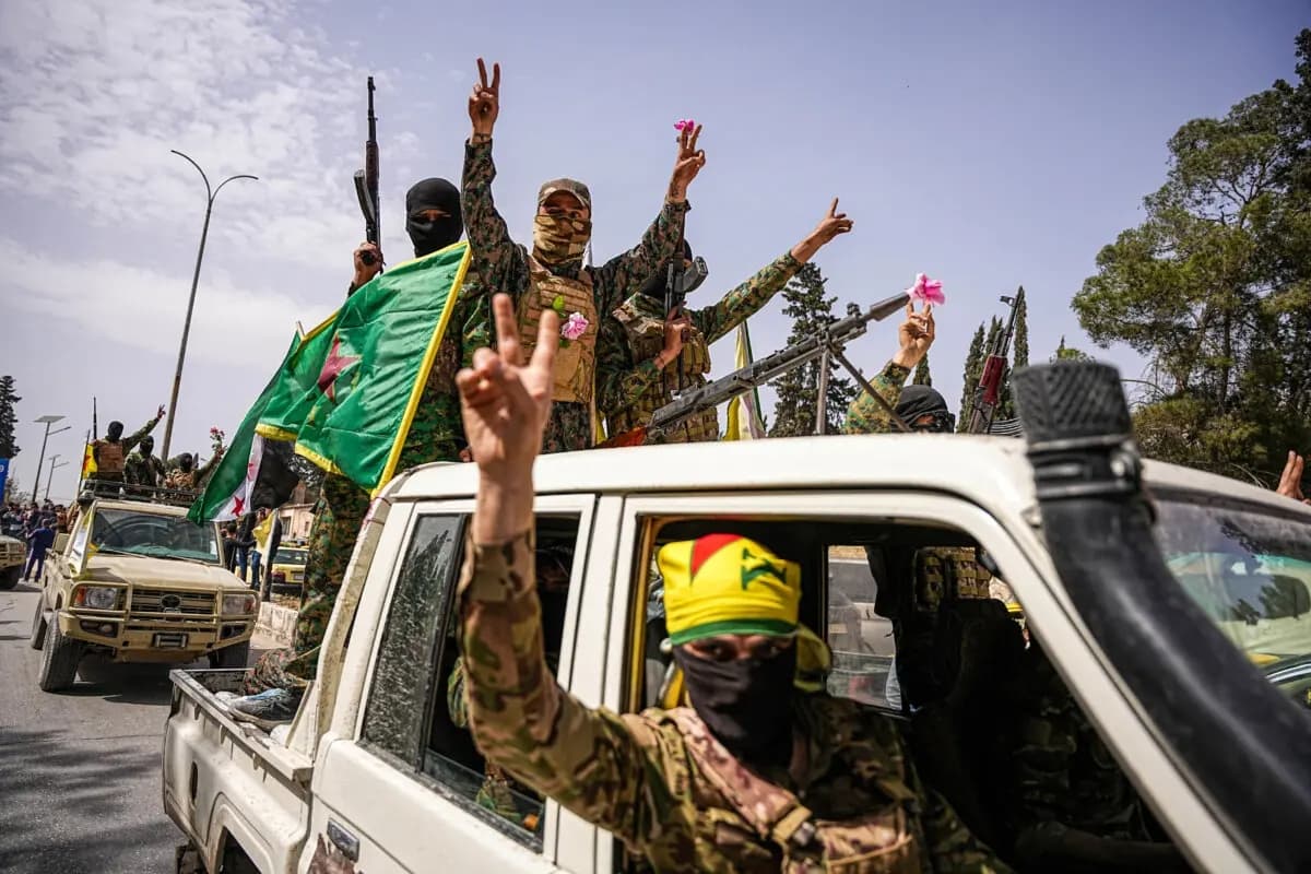 Combatientes de las SDF lideradas por kurdos ondean banderas desde un vehículo durante una procesión de convoyes al salir de Alepo, Siria, el 9 de abril de 2025. (Mohamad Daboul/Middle East Images/AFP a través de Getty Images)