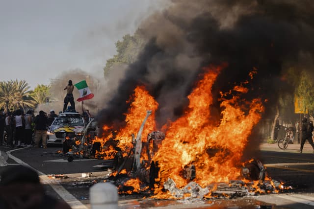 Varios autos incendiados en una calle del norte de Los Ángeles durante enfrentamientos entre manifestantes y policías el 8 de junio de 2025 en el centro de Los Ángeles, California. (Jim Vondruska/Getty Images)
