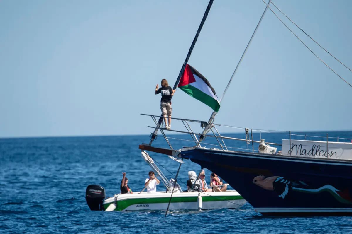 La activista climática Greta Thunberg junto a una bandera palestina en el velero Madleen en el puerto de Catania, Italia, el 1 de junio de 2025. (Salvatore Cavalli/AP)