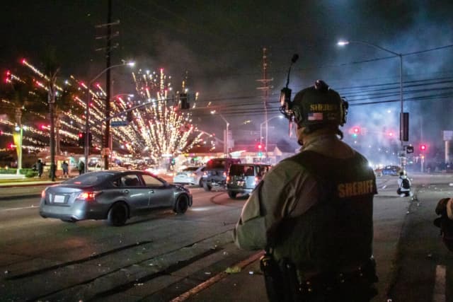 Un fuego artificial lanzado por manifestantes explota cerca de los oficiales del Departamento del Sheriff de Los Ángeles en Paramount, California, el 7 de junio de 2025. (Apu Gomes/Getty Images).