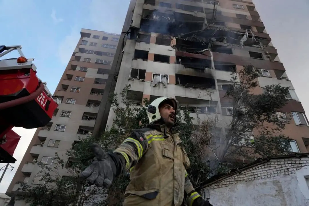 Un bombero llama a sus compañeros en el lugar de una explosión en un complejo residencial en el norte de Teherán el 13 de junio de 2025. (Vahid Salemi/AP Photo)