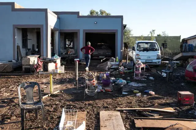 Una residente de un asentamiento informal gesticula mientras camina por su patio después de una inundación cerca de Mthatha (Sudáfrica) el 12 de junio de 2025. (Emmanuel Croset/AFP vía Getty Images)