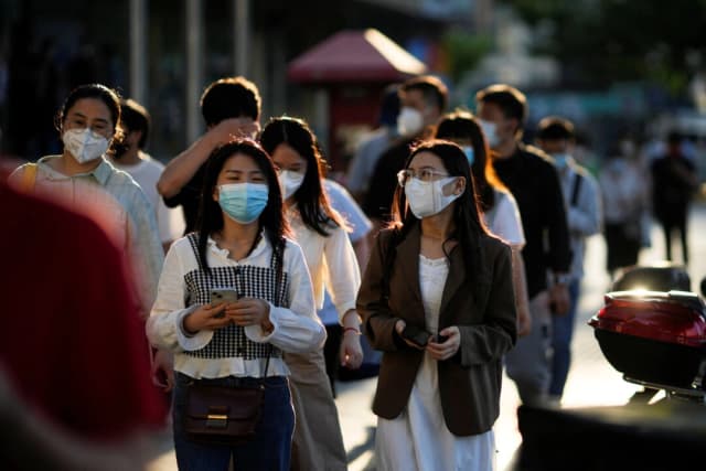 Personas con mascarillas caminan por una calle, tras el levantamiento del confinamiento impuesto para frenar el brote de coronavirus (COVID-19) en Shanghái, China, el 7 de junio de 2022. (Aly Song/Reuters)